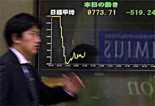 Un hombre de negocios de Tokio pasa por delante de un marcador que refleja el desplome de la Bolsa