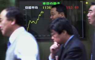 Hombres de negocios japoneses pasan ante un cartel que refleja los resultado de la Bolsa de Tokio