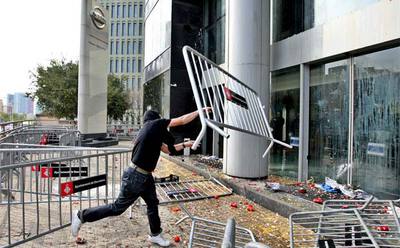 Un manifestante lanza una valla contra la sede comercial de Nissan en el centro de Barcelona.