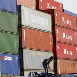 Un trabajador junto a los contenedores apilados en el puerto de Shanghai a la espera de embarque.