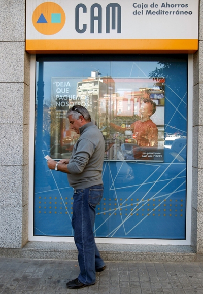 Un cliente consulta su libreta a la salida de una oficina de la CAM.