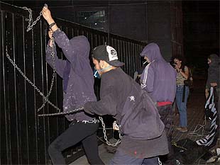 Tres jóvenes tratan de encadenarse a las puertas de los juzgados de Barcelona durante las protestas.