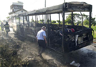 Agentes de la policía autónoma vasca y bomberos, en el autobús calcinado en San Sebastián.