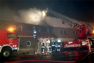Los bomberos tratan de sofocar el incendio ocurrido en el Club Alpino Español,  situado en el puerto de Navacerrada.
