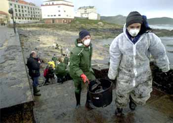 Voluntarios limpian el petróleo del paseo marítimo de Muxía, afectado por el vertido del petrolero.