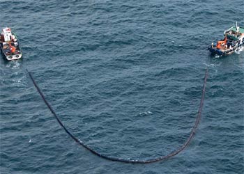 Dos barcos pesqueros intentan recoger el fuel flotante mediante un sistema de redes