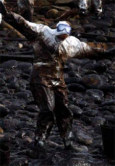 Un soldado trata de mantener el equilibrio entre el chapapote que mancha una playa cercana a Carnota.