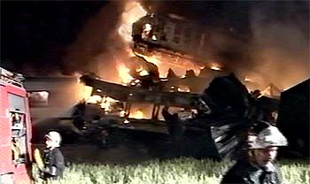 Los bomberos apagan el fuego en los vagones de los trenes incendiados tras la colisión.