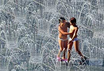 Dos niñas combaten el calor en Barcelona bañándose en una fuente.