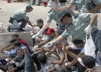 Agentes de la Guardia Civil reparten bocadillos a los 'sin papeles' recogidos en las costas de Almería.