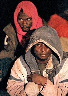 Un grupo de inmigrantes aguarda en el muelle de Gran Tarajal ser trasladados a dependencias policiales.