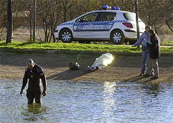 Bomberos y agentes de la policía inspeccionan el lugar de los hechos tras sacar del lago el cadáver.