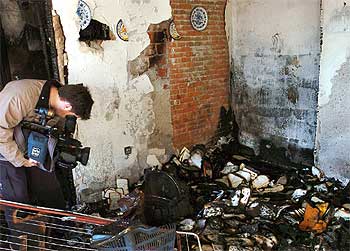 Un cámara de TV capta imágenes en una de las habitaciones del piso calcinado por las llamas en Coria del Rio.