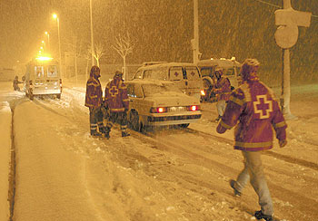 Miembros de la Cruz Roja asisten a algunos de los conductores que quedaron atrapados por la nieve en la autopista de peaje AP-1, a la altura de Miranda de Ebro.