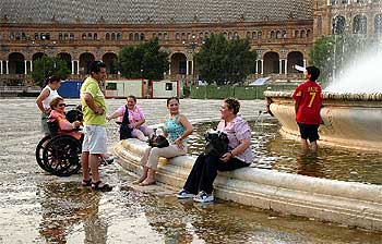 El calor llevó ayer a muchos sevillanos a refrescarse en las fuentes como la de la Plaza de España.