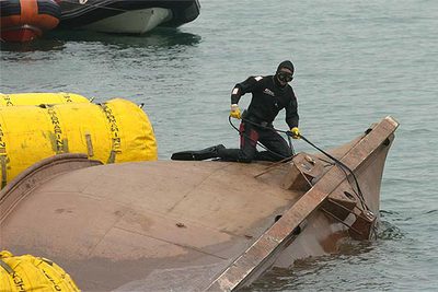 Un buzo de Salvamento Marítimo sobre la quilla del  Nuevo Pilín , durante las labores de reflotación de la embarcación en el Puerto de Bilbao.