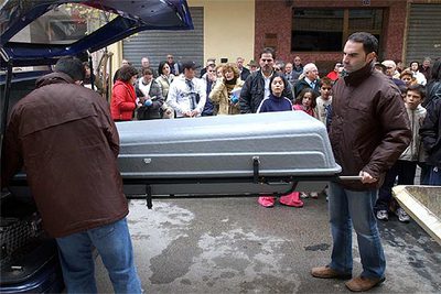 Unos operarios meten el féretro con el cadáver de Marta L.V, de 12 años, en un coche fúnebre ante numerosos vecinos.