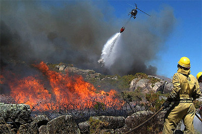 Dos miembros de una brigada contra incendios luchan contra las llamas que arrasa el monte de O Pindo en A Coruña.