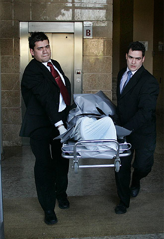 Dos empleados del Retén Funebre Judicial retiran el cuerpo de uno de los dos muertos en el piso de Valencia.