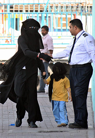 Michael Jackson, vestido con una  abaya  negra y un velo, saluda a un guarda de un centro comercial de Manama.