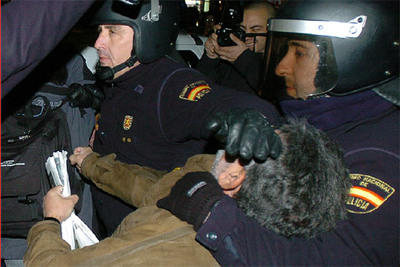 Dos policías retienen a uno de los participantes de la 