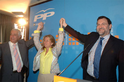 Rajoy (drcha.) y el presidente del PP andaluz, Javier Arenas, alzan las manos de María Angeles Muñoz.