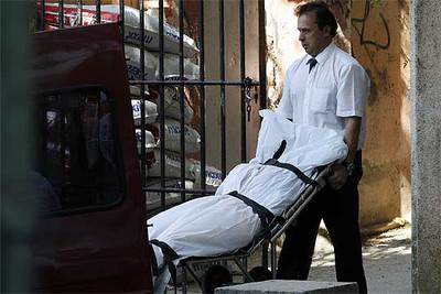 Un operario traslada el cadáver de la mujer del parque Quinta de los Molinos de Madrid, en San Blas.