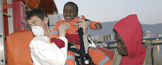 Un miembro de la Cruz Roja desembarca a uno de los bebés que llegó anoche a Motril en una patera con 68 inmigrantes.