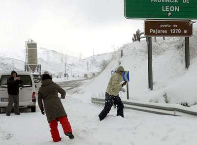 Varias personas se lanzan bolas de nieve en el Puerto de Pajares, en León, donde es necesario usar cadenas.