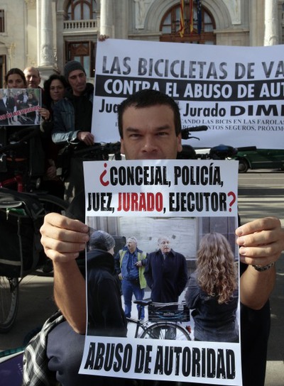 Uno de los manifestantes exhibe un cartel que exige la dimisión del concejal de Valencia que hizo retirar las bicicletas atadas a farolas.