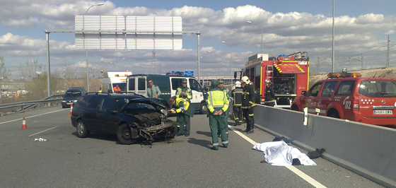 La víctima mortal de la colisión permanece tendida en el arcén, mientras agentes de la Guardia Civil analizan el vehículo.