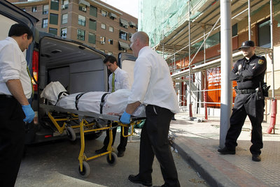 El cuerpo de uno de los dos obreros fallecidos es introducido en un furgón funerario.