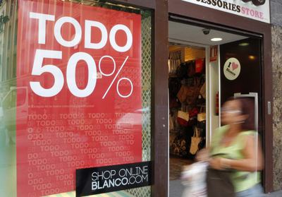 Una mujer pasa por delante de una tienda de moda en Madrid que desde hoy anuncia las rebajas de verano.