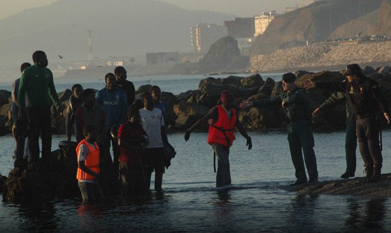 Unos guardias civiles ayudan a los inmigrantes llegados esta mañana a la playa ceutí de Tarajal.