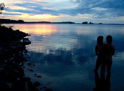 Una pareja de naturistas contempla el atardecer.