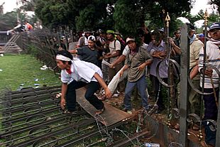 Los seguidores de Wahid derriban la primera barrera colocada por la policía alrededor del Parlamento.