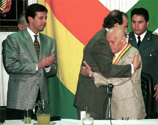 Hugo Banzer (derecha) es felicitado por el ministro de Educación Tito Oz De Vila mientras observa a la izquierda el Vice presidente Jorge Quiroga