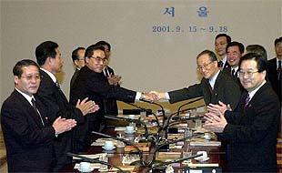 Los delegados ministeriales de ambas Coreas se dan la mano después de terminar las conversaciones mantenidas hoy en Seúl.