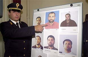 Un oficial de policía italiano muestra las fotos de los presuntos terroristas.