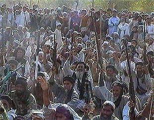 Decenas de hombres levantan sus armas, a la espera de cruzar la frontera.