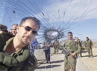 Solados israelíes miran el balazo que, atravesando el cristal, ha acabado con la vida de un colono esta mañana en un asentamiento al norte de Gaza.