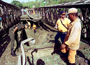 Varios policías examinan los desperfectos en un puente de Molino Viejo, a 70 kilómetros de Medellín, que el ELN voló ayer con dinamita.