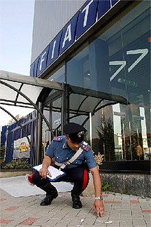 Un  carabinieri  recoge pruebas del artefacto explosivo colocado junto al concesionario de Fiat