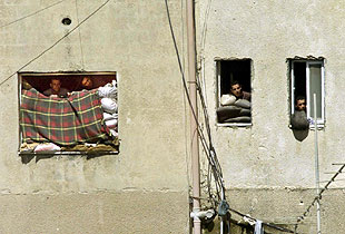 Varios palestinos observan la retirada de los tanques desde sus trincheras.