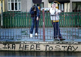 Dos niños norirlandeses, junto a un pintanda en la que se lee  El IRA está aquí para quedarse , en Londonderry.