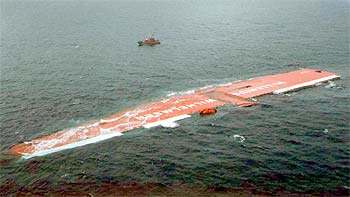 El carguero  Tricolor  yace en el canal de la Mancha poco antes de hundirse. En la foto superior el mismo barco en una imagen de archivo.