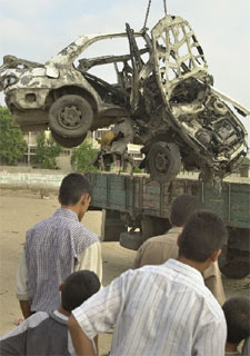 Jóvenes palestinos observan un coche alcanzado por misiles israelíes en Gaza.
