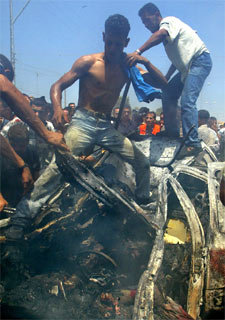 Varios palestinos intentan sacar los cadáveres de los restos del coche bombardeado por Israel.