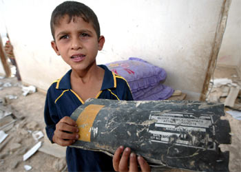 Un niño muestra un trozo de misil entre las ruinas de su casa en Gaza, atacada ayer por la aviación israelí.