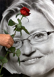 Un hombre deposita una rosa cerca de una foto de Anna Lindh colocada cerca del lugar donde se celebran los funerales.